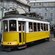 A vintage cablecar at a streetcorner, carrying passengers